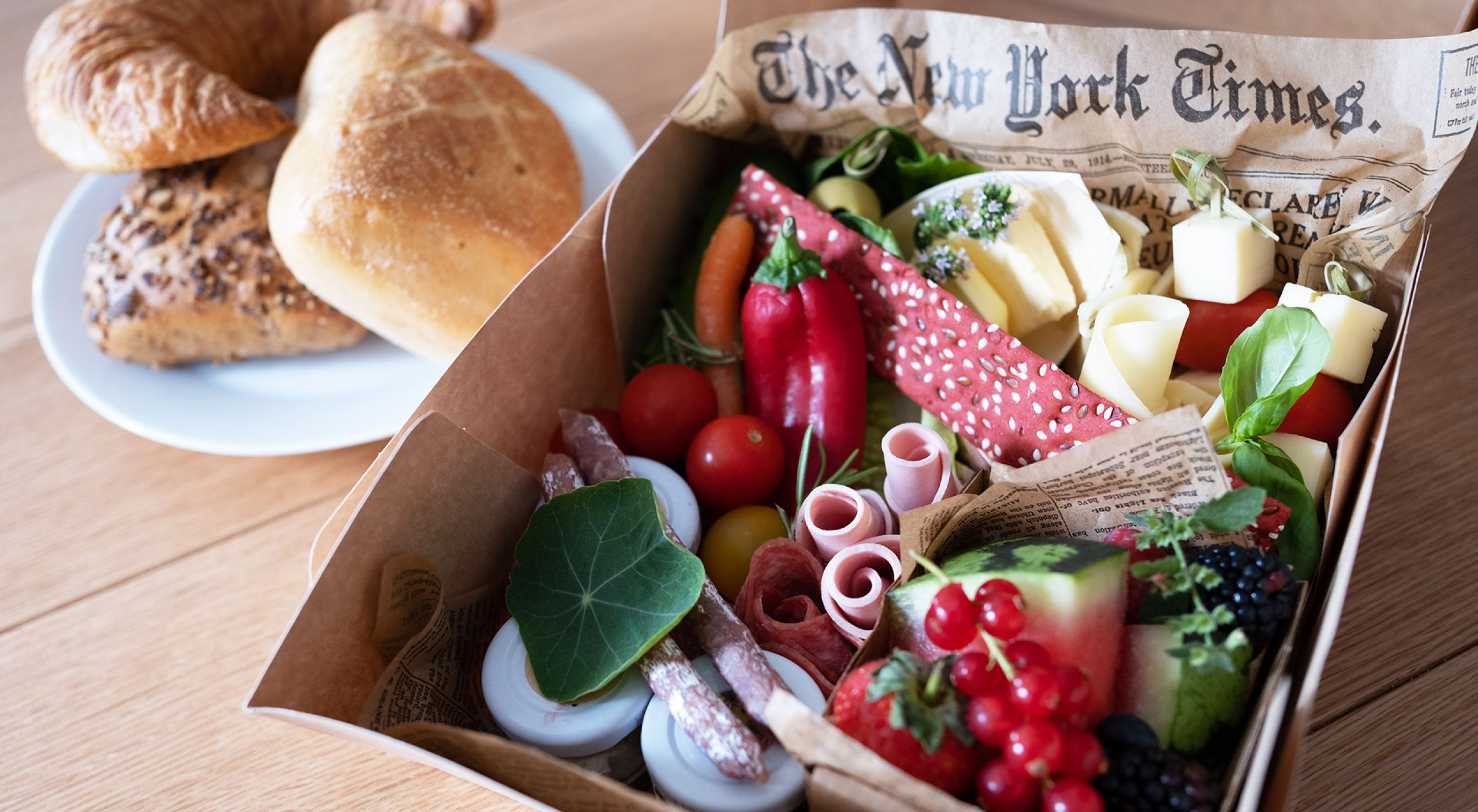 Frühstückskorb mit Brötchen, Wurst, Käse, Obst und Gemüse